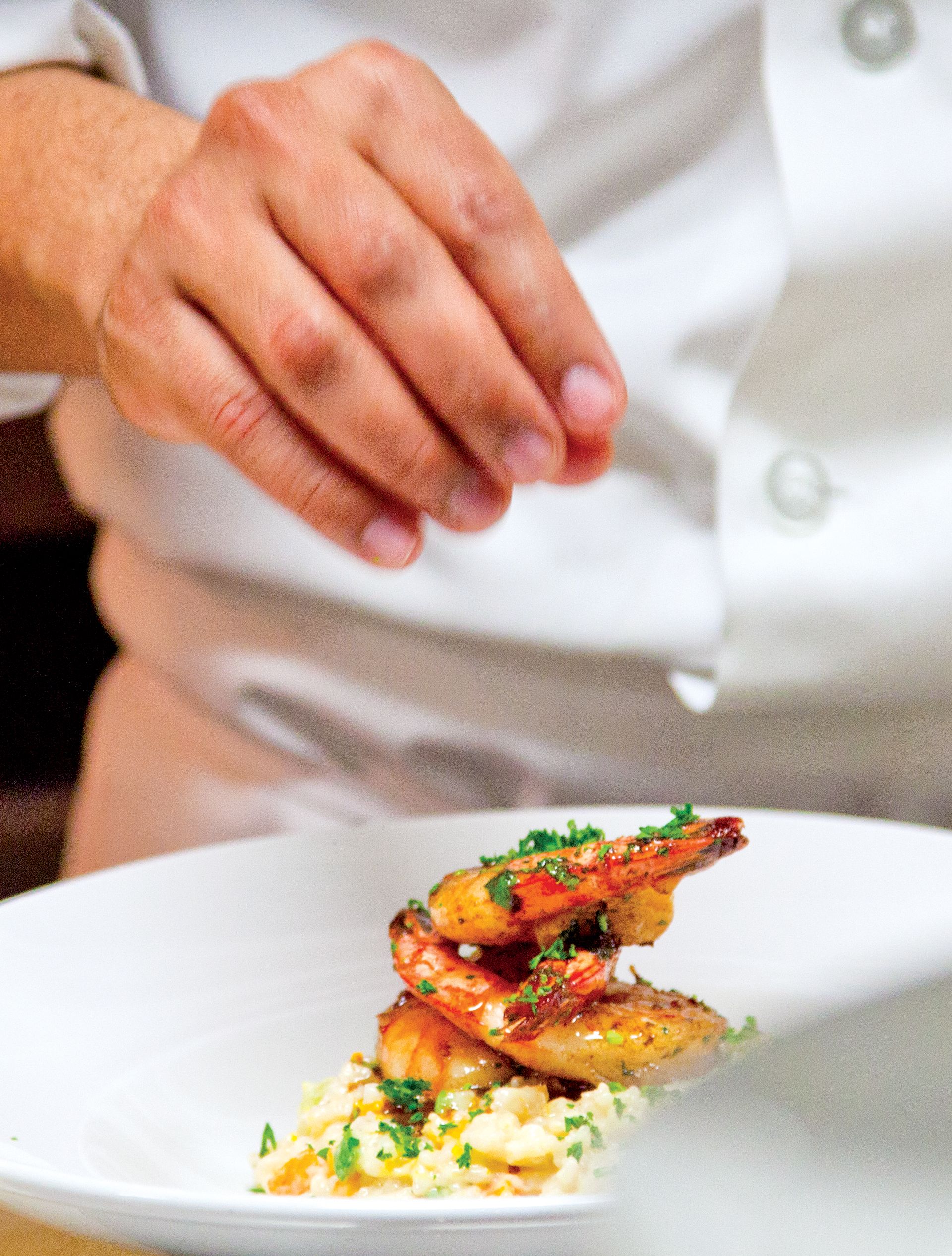 Chef Edgar Cobena Sprinkling Seasoning onto Seafood Dish